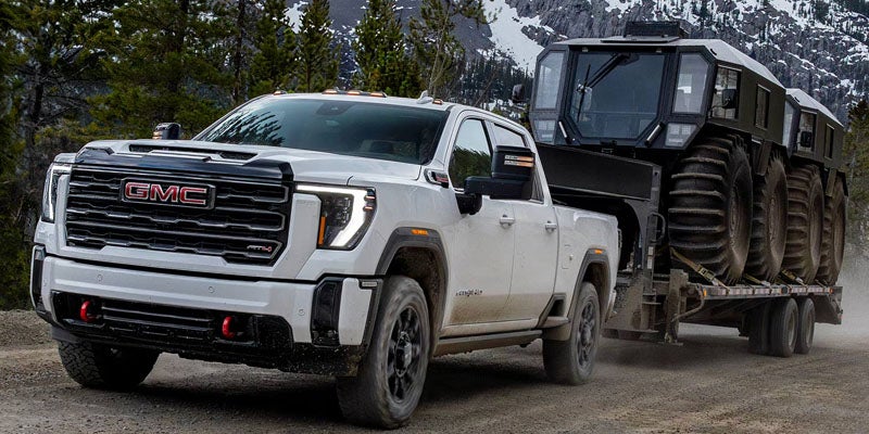 2026 GMC Sierra 2500 HD SLT towing heavy equipment to showcase its powerful capability