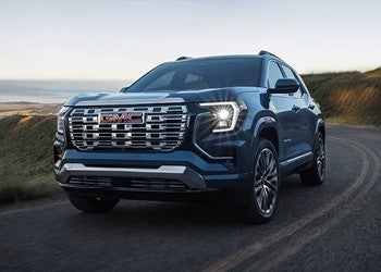 Blue GMC SUV driving on a winding road in a scenic landscape